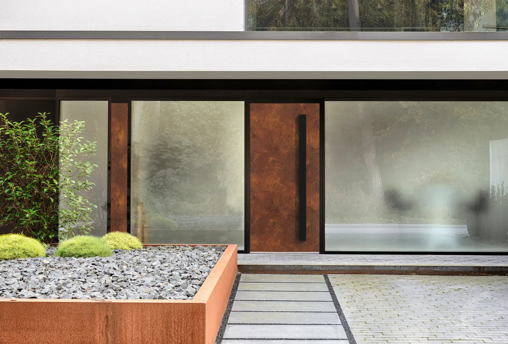 Haustür aus Cortenstahl mit schwarzem Stangengriff zwischen zwei satinierten Glasfronten